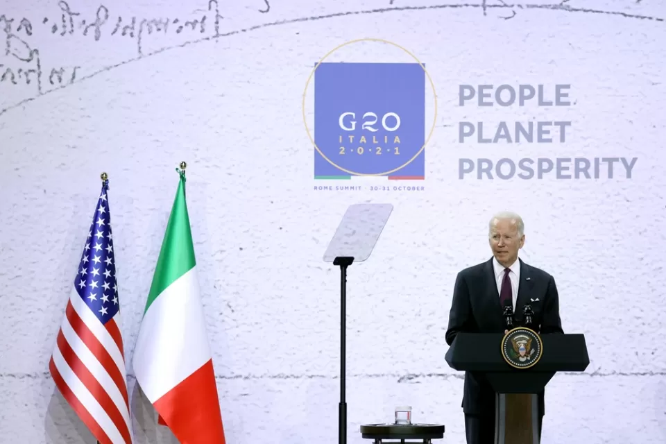 President Joe Biden speaks at a podium in front of flags from the United States and Italy at the 2021 G20 conference in Rome, Italy.